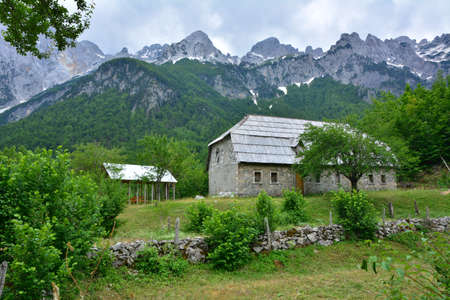 The Accursed Mountains in Albania .. Valbone Valley. The highest picks covered with snow. Green forest growing in the valley. Traditional Albanian house.の写真素材