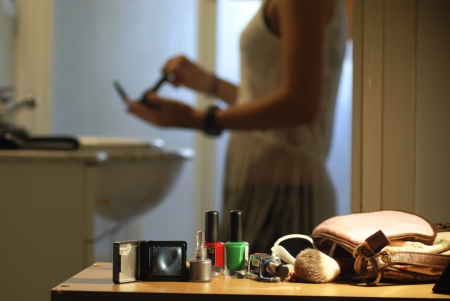 Set of makeup on the table while a girl at the back is putting on makeupの写真素材