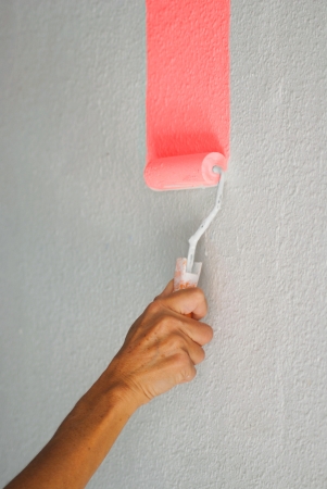 Painting pale pink colour wall with paint rollerの写真素材