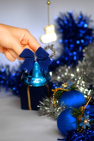 a hand picking up a Christmas bell with ornaments from behindの写真素材