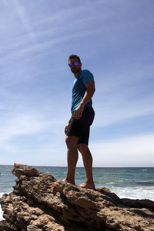 Guy on a rock on the beachの写真素材