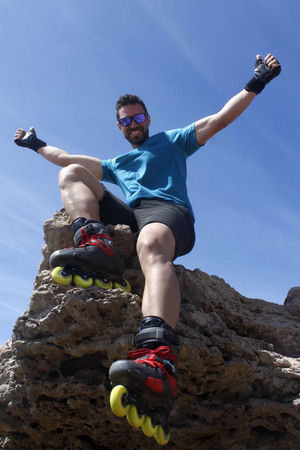 smiling guy on a rock with skates with his hands upの写真素材