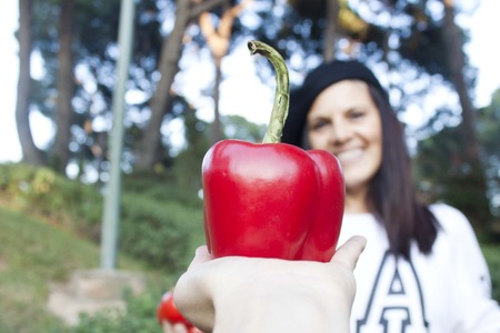 woman smiling behind a red pepperの写真素材