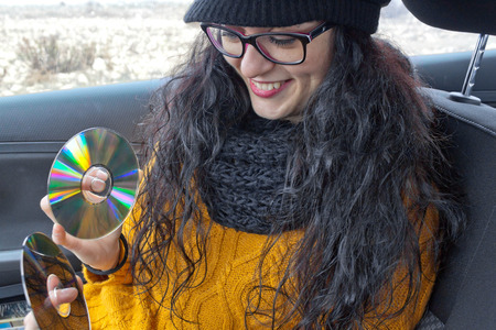 Girl very happy in a car with two cdsの写真素材