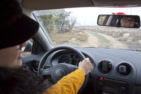 woman looking in the rear mirror of her carの写真素材