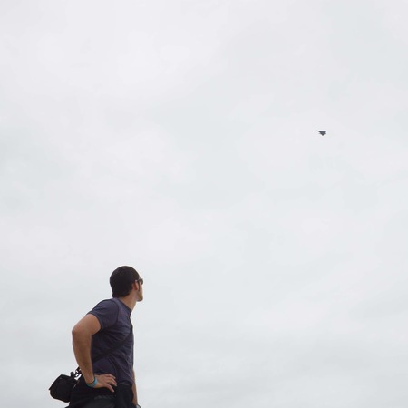 guy looking up to a fighter plane in the cloudy skyの写真素材