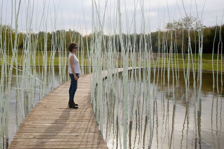 woman in a wooden path over a lake contemplatingの写真素材
