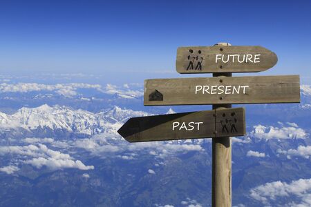 three signs indicating the way to the past, present and future over the mountainsの写真素材
