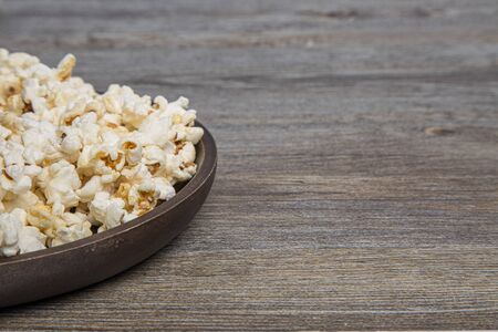 Fresh popcorn in a bowl on a rustic tableの写真素材
