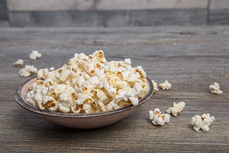 Fresh popcorn in a bowl on a rustic tableの写真素材