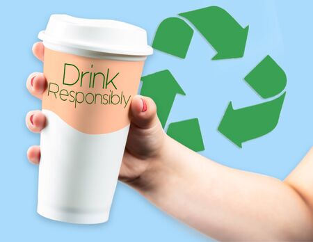 Recycle Logo behind Takeaway Coffee Cup held in young female handの写真素材