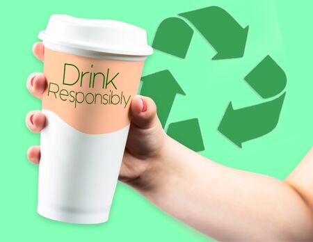 Recycle Logo behind Takeaway Coffee Cup held in young female handの写真素材