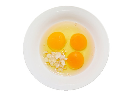 eggs mixed with sliced fresh onion in a bowl on white background.の写真素材