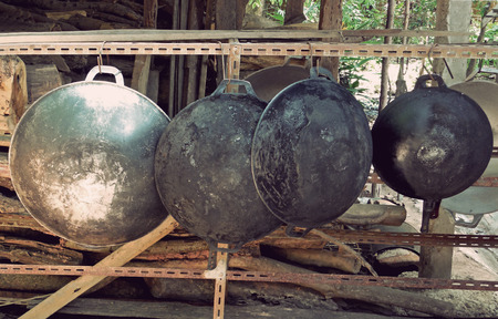 old and dirty black pans hanging on the rackの写真素材