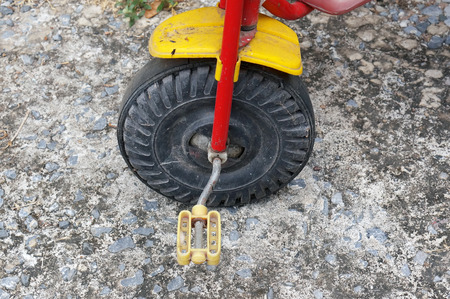 close up wheel of old tricycle on dirty concrete ground