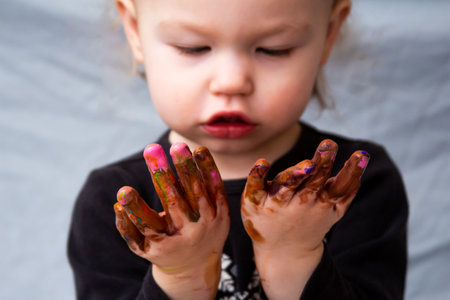 toddler looking at you messy finger paint handsの写真素材