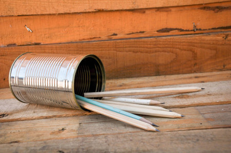 Pencils in a tin can on a wooden floor
