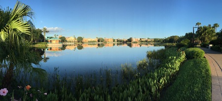 Mirrored Image of Sun-lit Buildings on a Calm Still Lake During a Cloudless Blue Sky Day