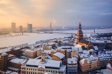 View of the roofs of the old city and the tower of the Dome Cathedral against the background of an ice-covered river. Winter evening in Riga. Latvia.の写真素材