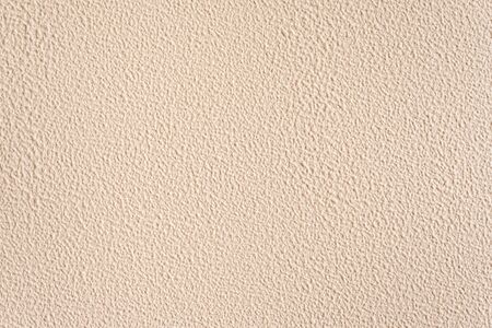 Textured nude background. Decorative plastering, external decoration of the facade. Background image of a wall with beige rough coating.の写真素材
