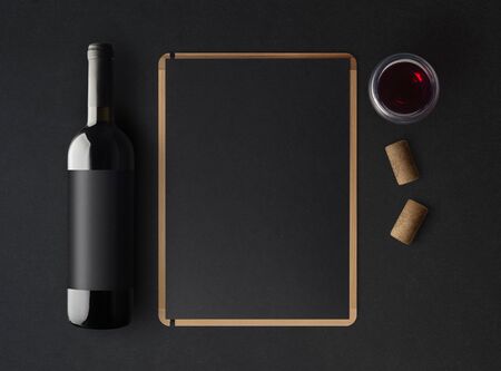 Bottle of red wine with a black label on a dark background, a wine menu template and a glass of wine. Mockup. Top view.の写真素材