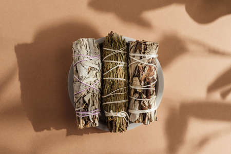 White sage, cedar, yerba santa tied in a bunch on a concrete plate. Set of incense for fumigation,...