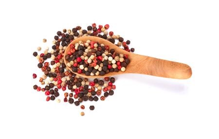 Coloured pepper on a wooden spoon isolated on white