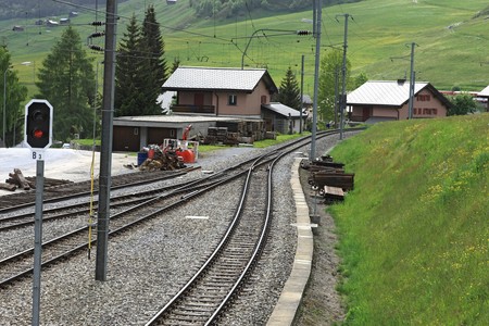 Railroad tracks with electricity poles leading through a village in the alpsの写真素材