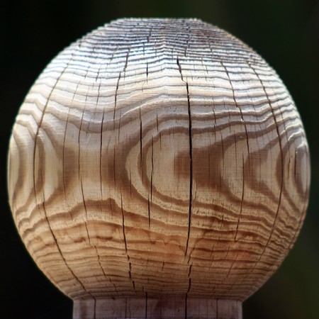 Close view of a grained wood fence post on a dark backgroundの写真素材