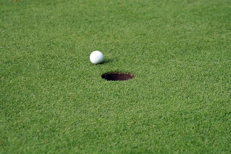 Golfball in front of the holeの写真素材