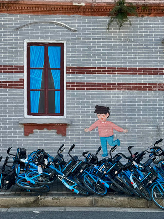 colorful mural amidst discarded bicycles, playful child figure painted on cluttered city wall scene, vibrant mural of child sparks contrast against jumble of bicycles and industrial surroundings Shanghaiの写真素材