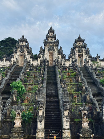 The gate overlooking the volcano of Pura Penataran Agung Lempuyang is a Balinese Hindu temple in Bali, Indonesia. ornate gateways frame mossy steps, lush hillside adorned with weathered shrinesの写真素材
