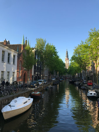 Amsterdam, Netherlands, May 8, 2018, boats tranquil canal with city reflections, peaceful waterside...