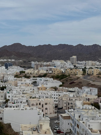 White Arabic houses at foot of rocky desert mountains in Muscat, Omanの写真素材