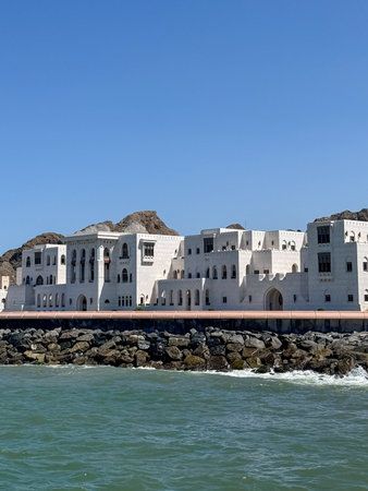 White Arabic style seafront palace in Muscat, Oman with mountains and blue skyのeditorial素材