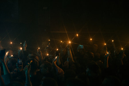 Warsaw, Poland, October 22, 2025 Concert crowd holding smartphones with lights in dark venueのeditorial素材