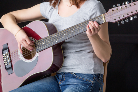 girl in a hat with a guitar sitting on a bar stool