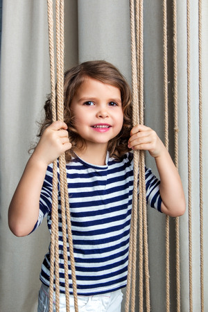 child standing and holding on to a rope seaの写真素材