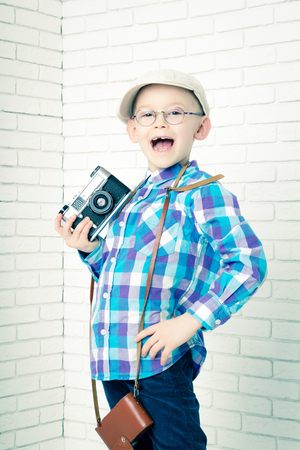 Little boy in a cap with retro camera. Stands and shoutsの写真素材