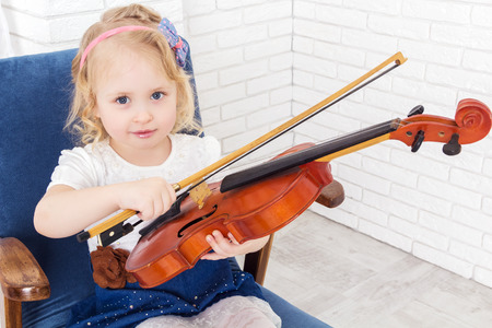 little girl with a violin and bow, looking at cameraの写真素材