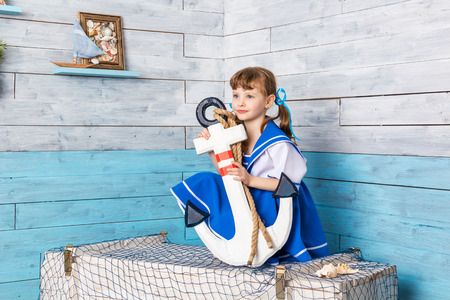 little girl sitting and holding an anchor, looking awayの写真素材