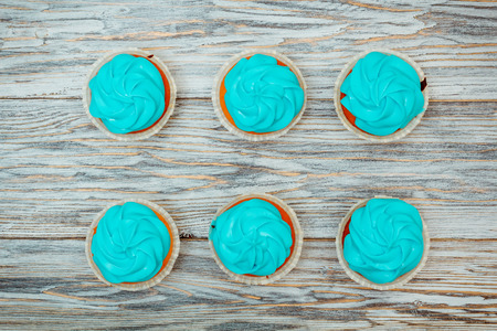 Cupcakes with blue cream on old boards, flat layの写真素材
