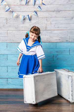 little girl holding a suitcase and laughing, looking downの写真素材