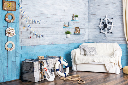 interior in maritime style: sofa, box, helm, anchor and life preserverの写真素材