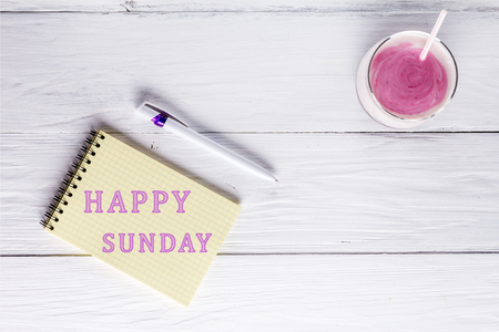 Berry smoothie and an inscription in notebook: Happy sunday. Flat layの写真素材