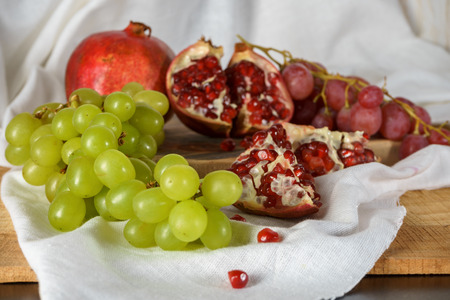 Red and green grapes with pomegranate on a kitchen table. Close upの写真素材