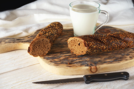Breakfast: glass of milk and loaf. Closeup