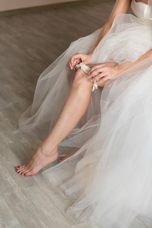 the bride in a wedding dress on an elegant dress garter legの写真素材