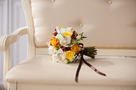 delicate bouquet of the bride on a beige couch in a classic interiorの写真素材