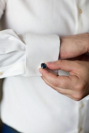 the groom dresses blue cuff links on a shirt
